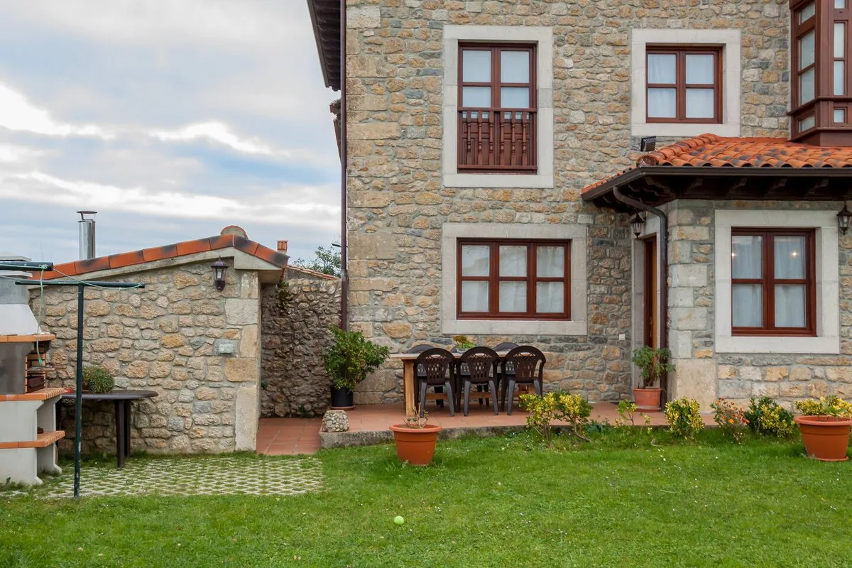 Porche con barbacoa y mesa exterior junto al jardín